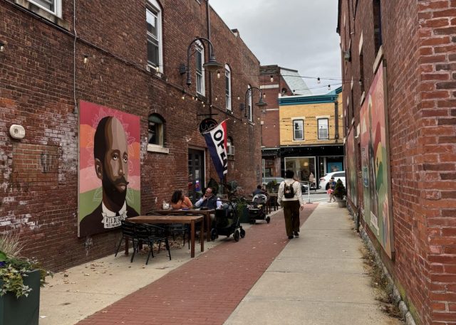 Photo of an alleyway with brick and public art on the walls.
